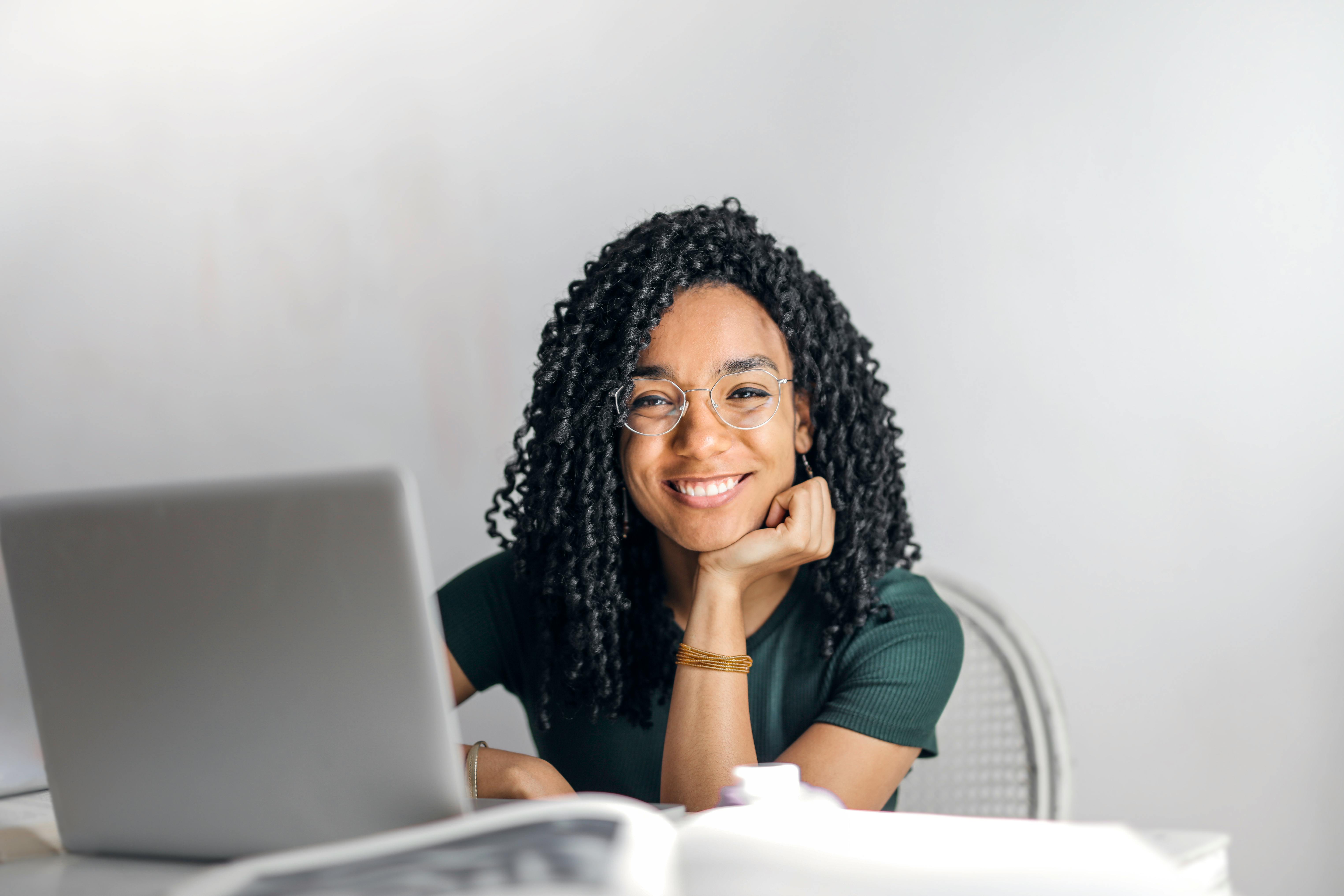 Mujer frente a una computadora portátil, sonriendo a la cámara